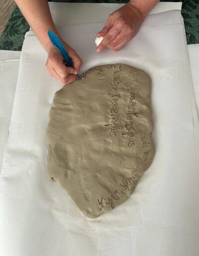Mains inscrivant des mots dans une plaque d’argile.